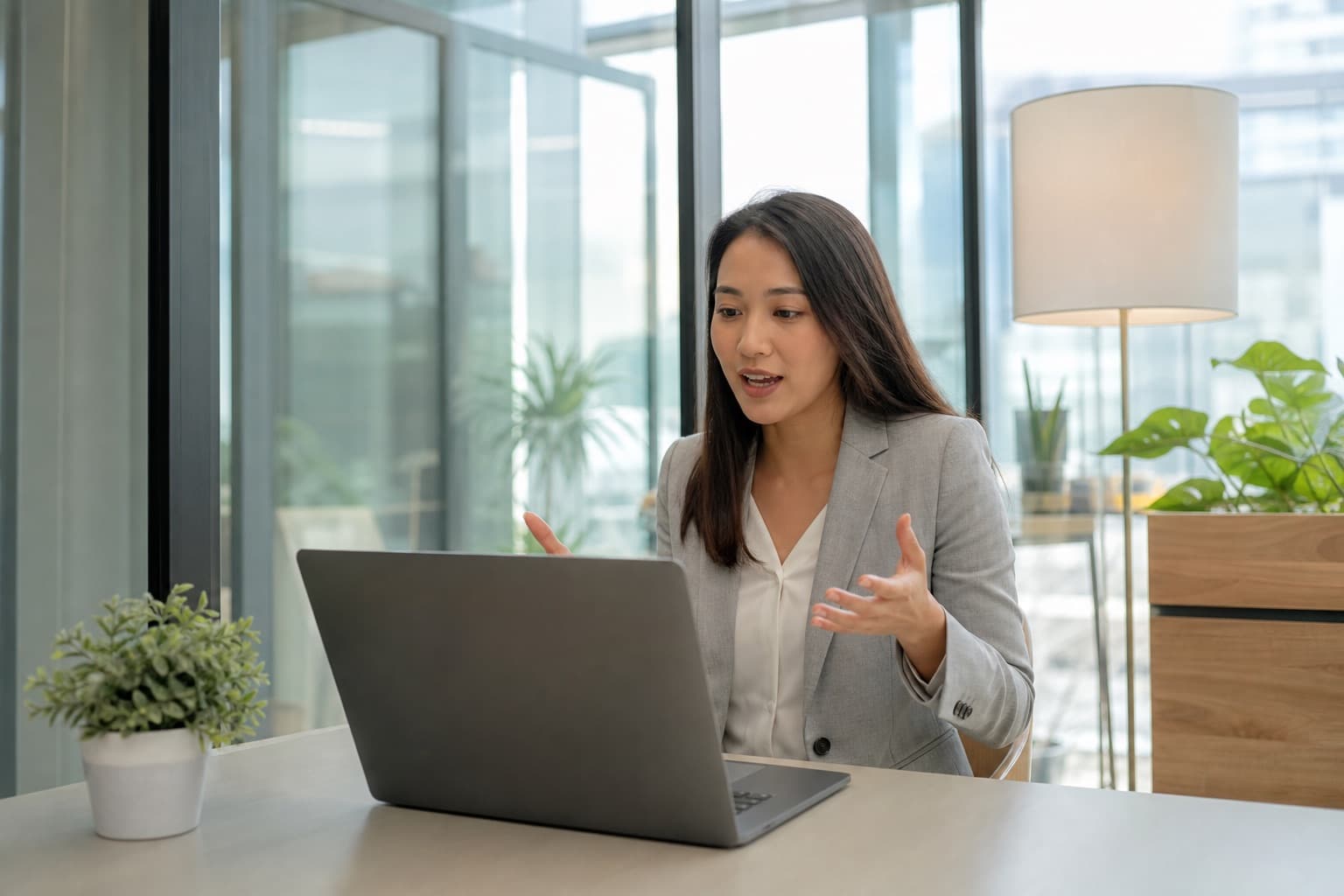 A candidate practicing interview answers out loud at a laptop in a bright office